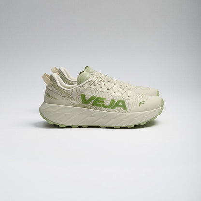A pair of Hoka Veja running shoes in a light cream and sage green colorway, shown from a side profile against a neutral gray studio background.