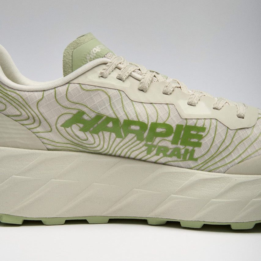 A close-up side view of a Harpie Trail sneaker in off-white and light green, featuring a thick textured sole and &
