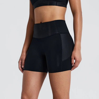 A model wearing black high-waisted athletic shorts with textured side panels, shown from the waist down against a light gray studio background.
